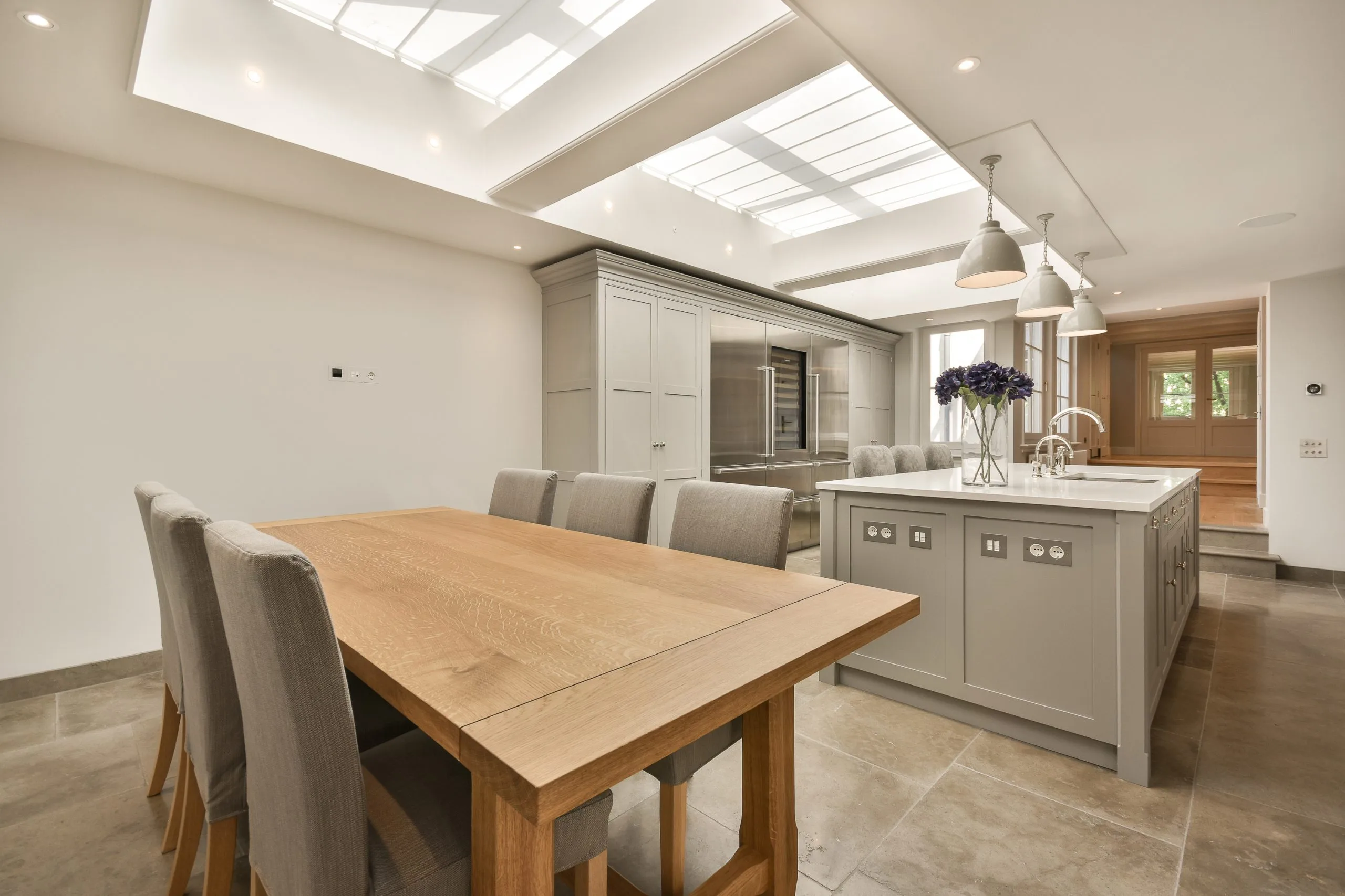 a large kitchen with a wooden table and grey cabinets